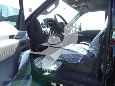 Ford F750 interior cockpit view showing driver seat and dashboard with plastic seat cover and paperwork on floor.