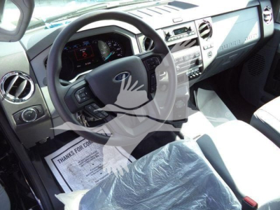 Ford F-Series cab interior with steering wheel, dashboard, and center console; visible instrumentation cluster and driver seat covered in protective material.