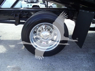 Ford F-750 rollback truck wheel and undercarriage view showing chrome wheel with lug nuts and black frame components.