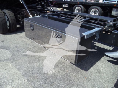 Truck bed tool box mounted on a Ford F-750 chassis showing a rectangular aluminum/steel toolbox with latch handles.