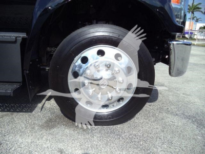 Truck front wheel and fender shown; chrome wheel with multiple lug holes; tread visible; part of step/side platform; no legible labels or text visible on fuel or engine components.