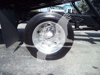 Wheel and suspension of a Ford F750 rollback truck showing polished steel wheel and tire with undercarriage components.