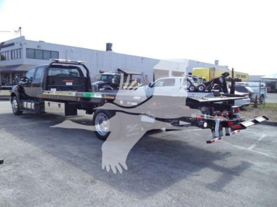 Ford F-750 truck with rollback bed and tow equipment, viewed from side in an outdoor lot.