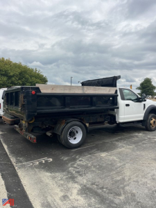 Ford F-550 dump truck in-service showing side view with dual rear wheels and black dump bed attached to white cab.