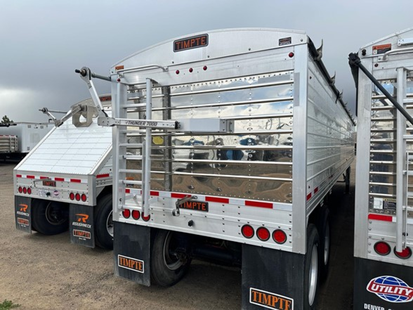 Timpte Super Hopper trailer rear view with polished metal side panels, black mud flaps, and Timpte branding on the tailgate.