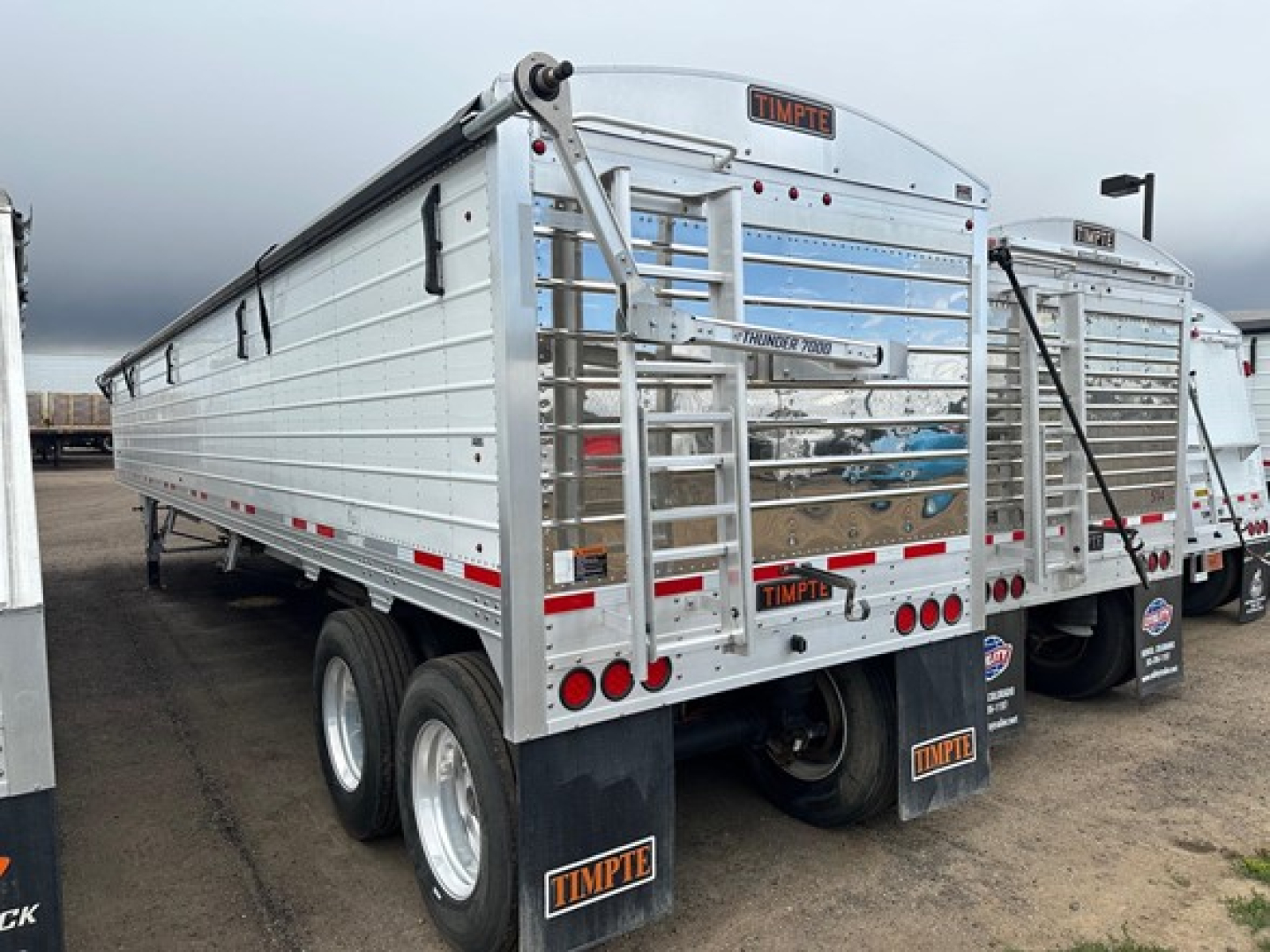 Rear view of a Timpe "Timpte" hopper trailer with dual rear axles, metal side panels, and ladder. Visible text: TIMPTE on rear plate, rear bumper license plate area, and small badges.