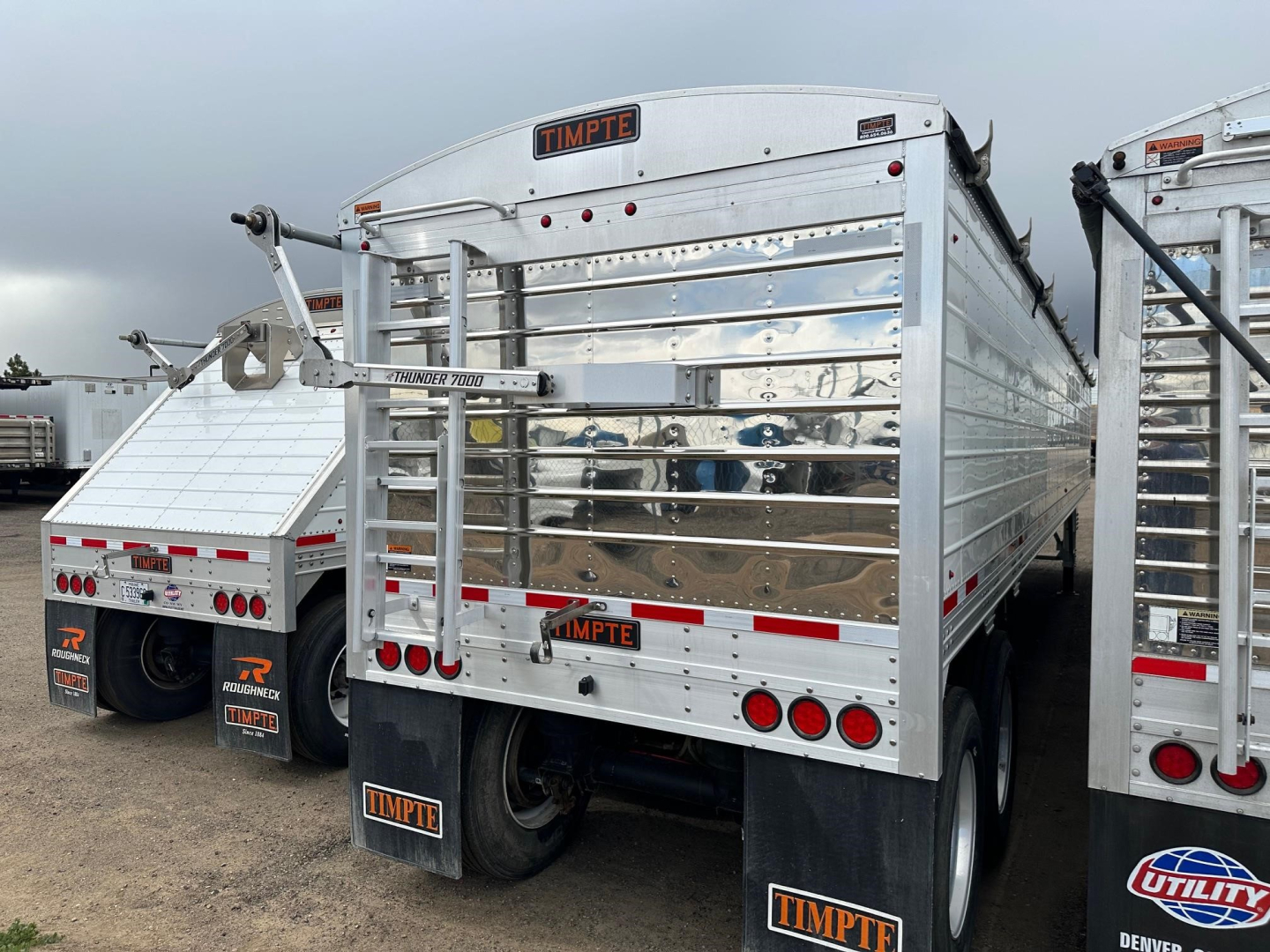 Timpte Super Hopper trailer rear view showing reflective metal sides, rear gates, and mudflaps with Timpte logos.