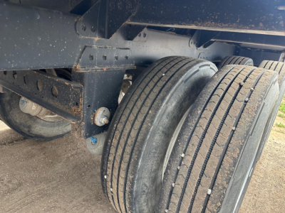 Trailer wheel assembly showing dual tires and suspension undercarriage of a Timpte hopper trailer with visible steel frame and mud residue.