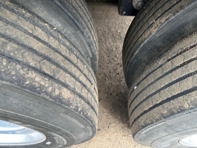 Timpte Super Hopper trailer tires and mud on tread with dual wheels visible, left and right wheels with rims, surface dust.