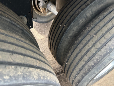 Trailer axle with dual tires and visible suspension components in view.
