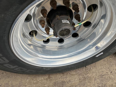 Timpte Super Hopper trailer wheel and hub showing polished aluminum rim, lug nuts with rust marks, and black hub with sticker; tire tread visible.