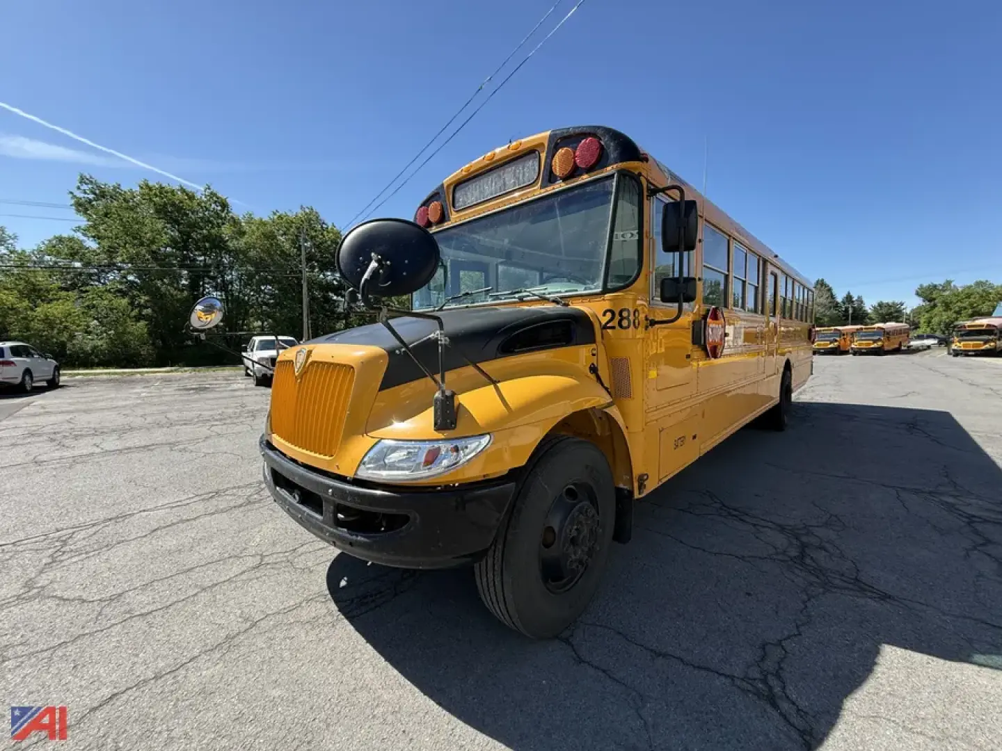 School bus front-left view showing CE series yellow IC Corporation bus with black front bumper and mirror, round bus stop arm, and multiple orange lights on the roof.
