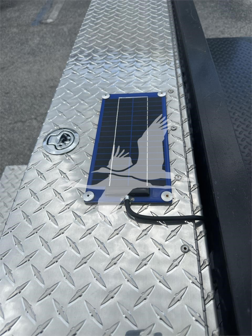 Solar panel and diamond plate trailer step with mounted solar charging panel and cable visible on aluminum deck.