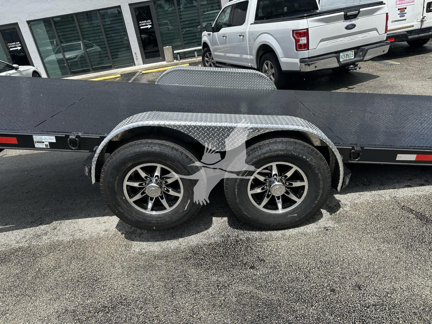 Trailer wheel well with dual tires and diamond plate fender on a flatbed trailer.