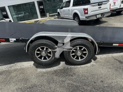Trailer wheel well with dual tires and diamond plate fender on a flatbed trailer.