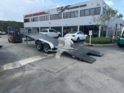 Trailer loading ramp with dual axle and long flatbed, in front of a service building with TCL Trailers Corp sign.