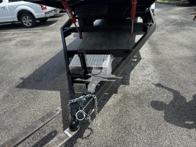Trailer hitch and front frame of a new trailer showing hitch coupler and safety chains with diamond plate toolbox.