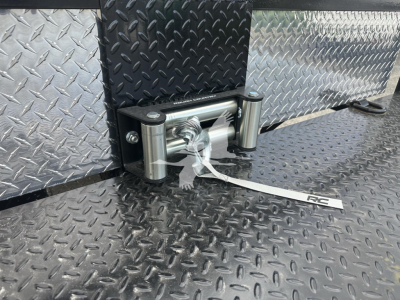 Trailer hitch with coupler and silver diamond-plate exterior, side-mounted mechanism, and tethered tag showing FZTR00733FM on a black textured surface.