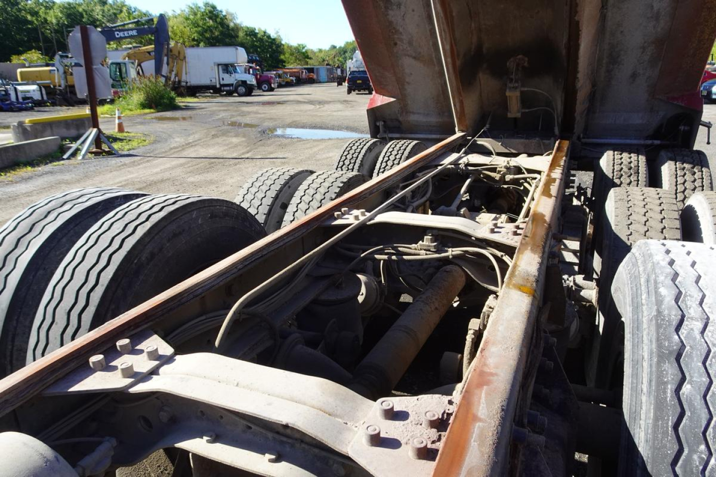 Chassis area of a 2004 Mack RD RD688S dump truck showing frame rails, drive shaft, and rear suspension with dual rear axles and raised dump bed.