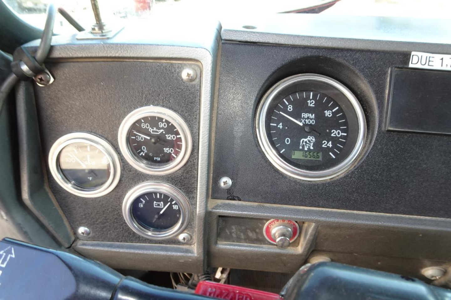 Dashboard of a Mack RD RD688S showing multiple gauges including RPM gauge, speedometer, and auxiliary gauges; visible sticker 'DUE 1' on top right; various chrome ringed gauges.