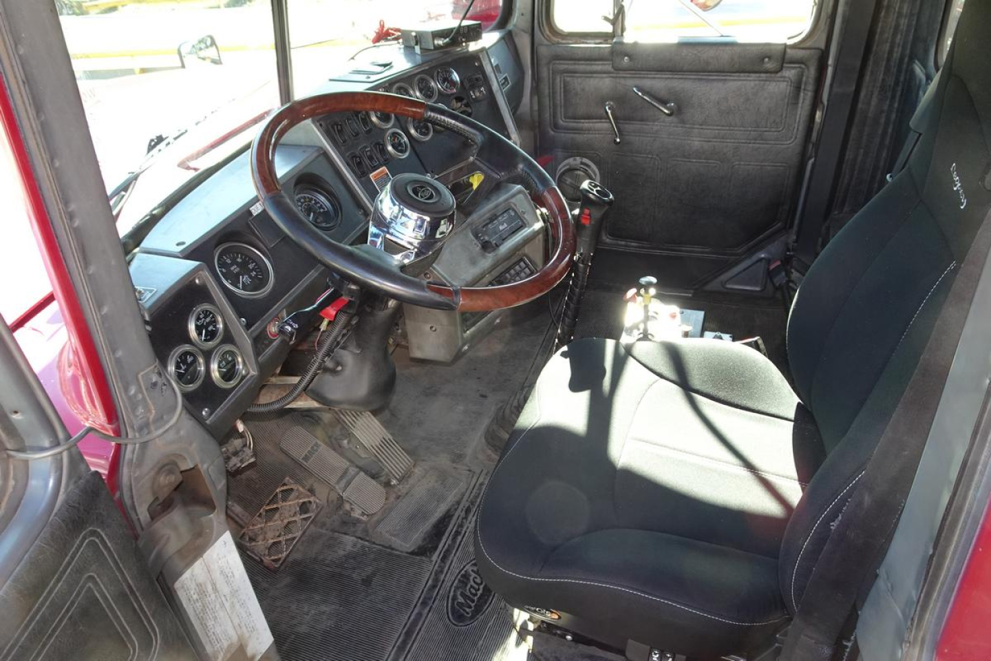 Truck interior showing steering wheel, dashboard gauges, and manual shifter in a Mack RD RD688S dump truck cab.