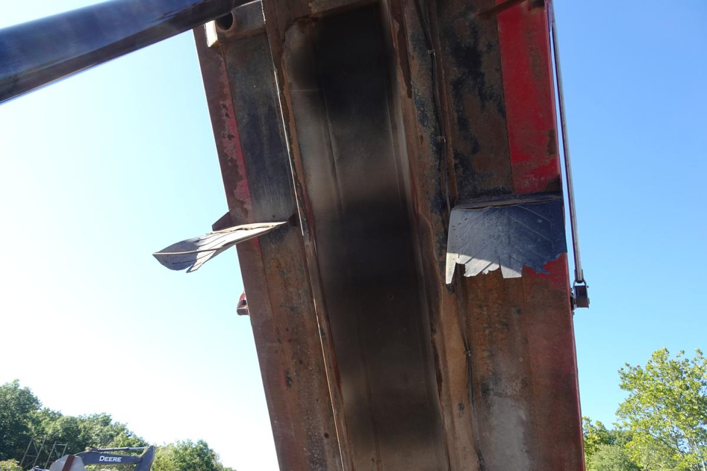 Dump truck bed underside showing metal frame and hydraulic components.