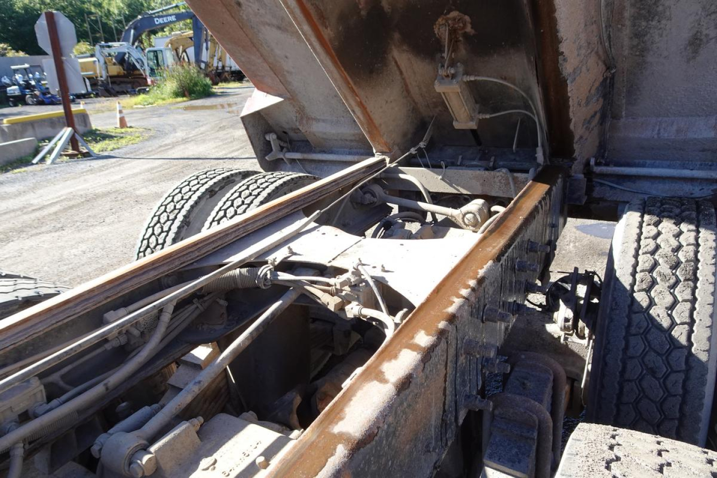 Mack RD688S dump truck chassis with raised bed showing hydraulic lines and frame rails.