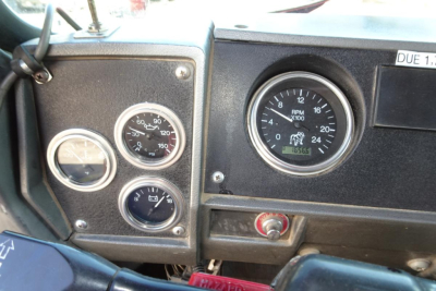 Dashboard of a Mack RD RD688S showing multiple gauges including RPM gauge, speedometer, and auxiliary gauges; visible sticker 'DUE 1' on top right; various chrome ringed gauges.