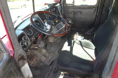 Truck interior showing steering wheel, dashboard gauges, and manual shifter in a Mack RD RD688S dump truck cab.