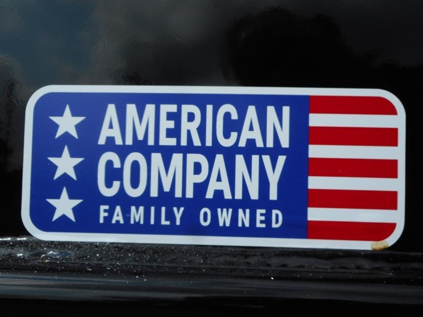 Sticker on a vehicle reading AMERICAN COMPANY FAMILY OWNED with white stars on blue background and red and white stripes.