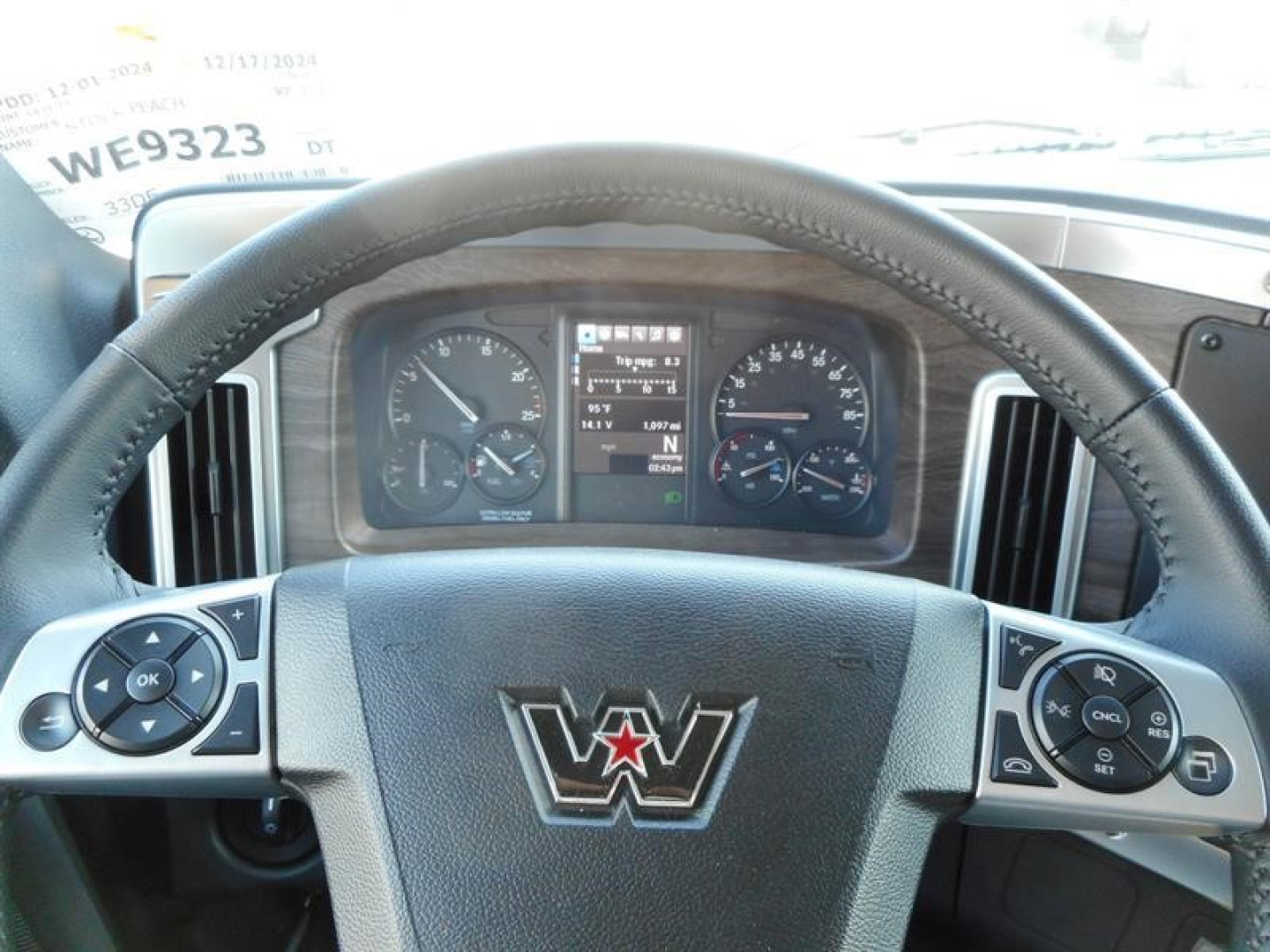 Cockpit view of a new Western Star 47X truck dash with steering wheel center emblem and gauge cluster visible through the windshield.
