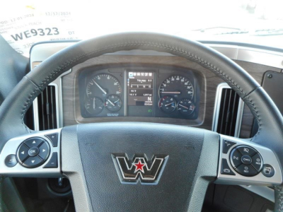 Cockpit view of a new Western Star 47X truck dash with steering wheel center emblem and gauge cluster visible through the windshield.
