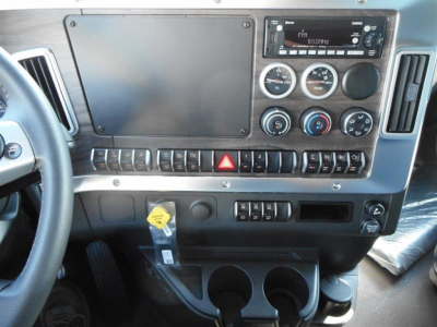 Dashboard interior of a Western Star 47X showing a large blank/covered screen, circular gauges, climate controls, radio unit, hazard button, switch panel, key tag, and cup holders.