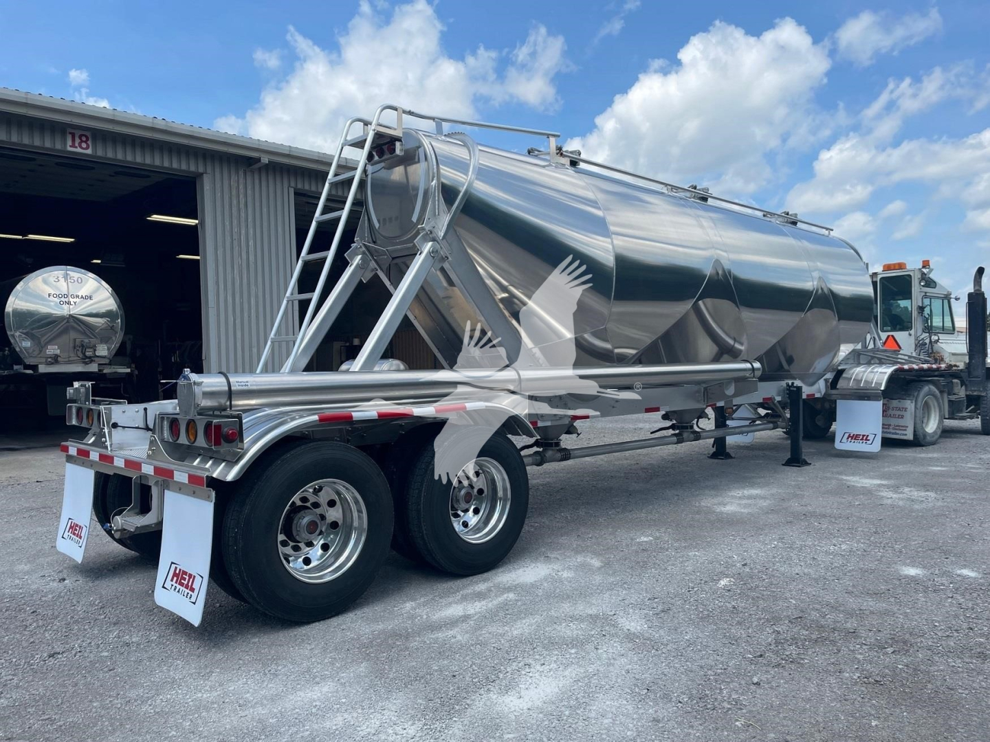 Heil Super Jet 1040 pneumatic dry bulk trailer side and rear view showing polished stainless steel tanker and dual rear axles with mud flaps.