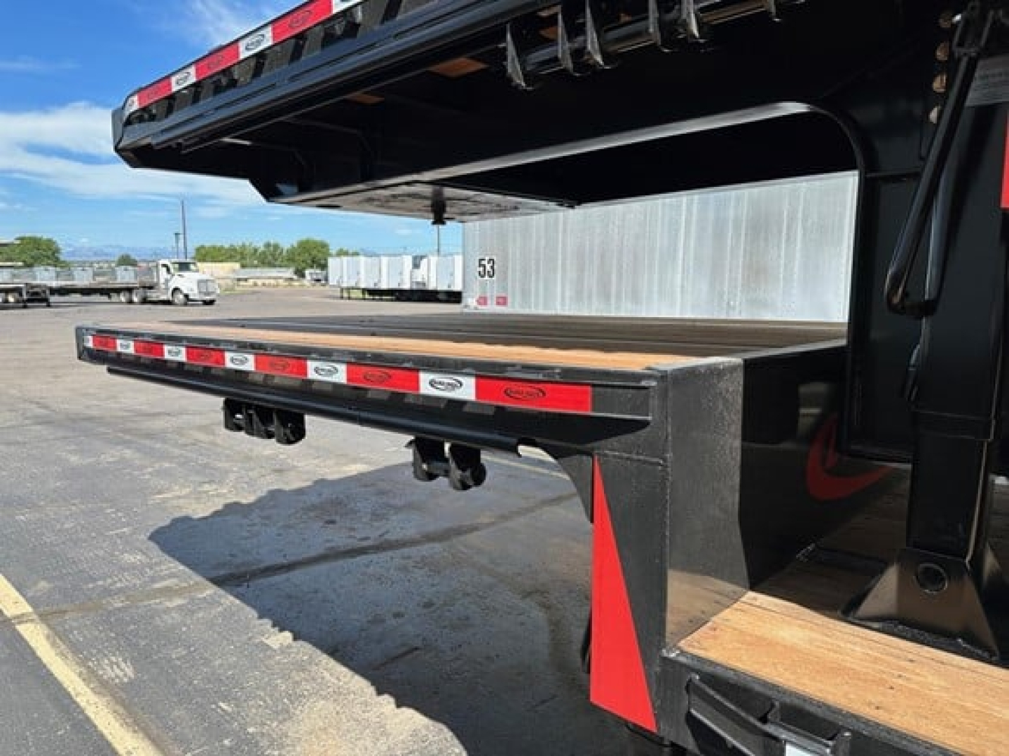 Trailer deck with beavertail and drop deck feature showing a flat steel bed and red/white reflective tape on the edges.