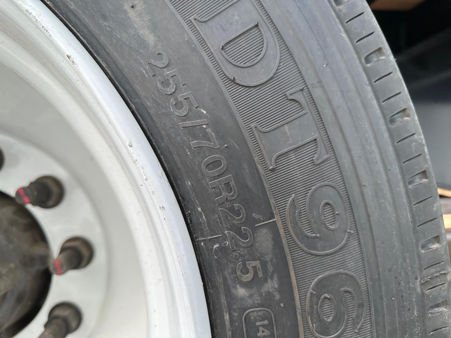 Truck trailer tire with visible sidewall markings and wheel, showing tire model and numerical codes.
