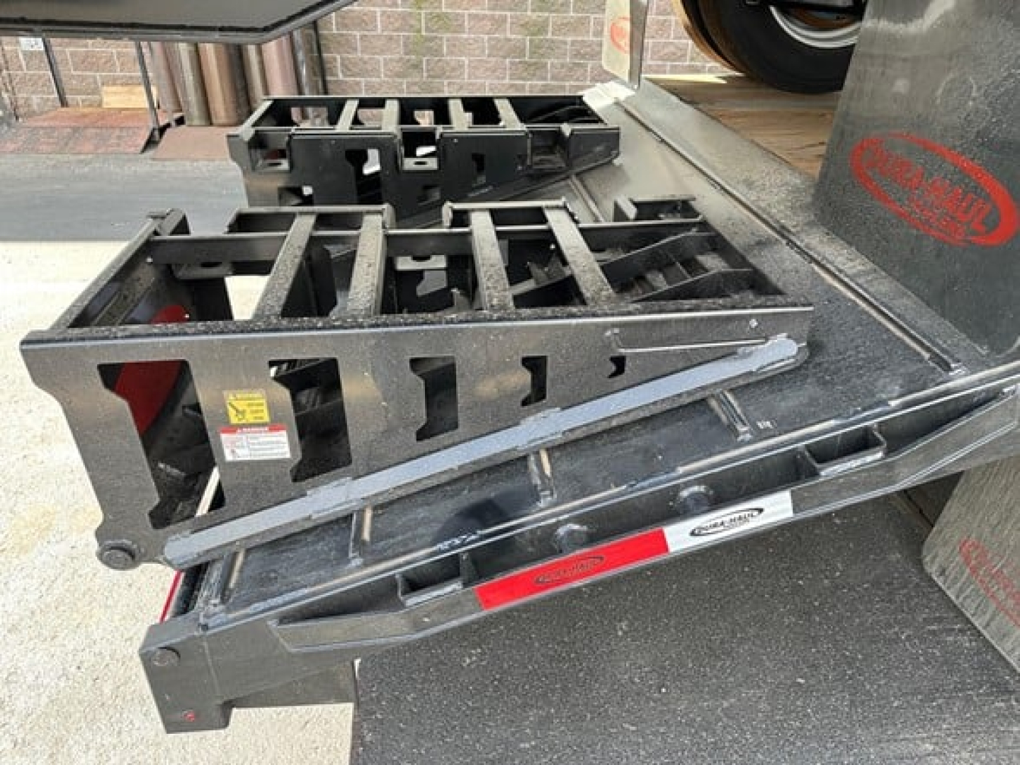 Trailer docking with drop deck and beavertail showing metal frame components and warning labels.