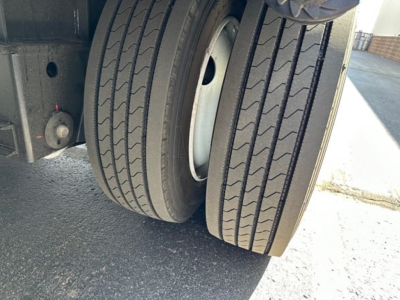 Trailer rear dual tires and part of drop deck chassis undercarriage showing heavy-duty wheel assembly and spring mount.