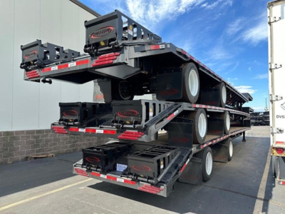 Trailer stack showing a 53' steel drop deck with Beaver tail from Dura Haul; multiple axles and wheels with black steel frame and red/white reflective markings.