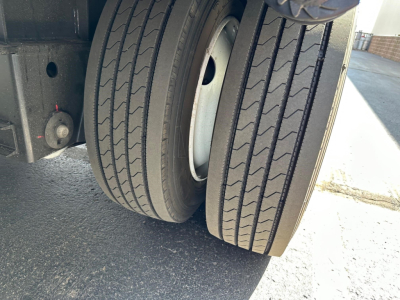 Trailer wheel pair and beavertail section of a Dura Haul steel drop deck trailer showing dual rear tires and part of suspension.