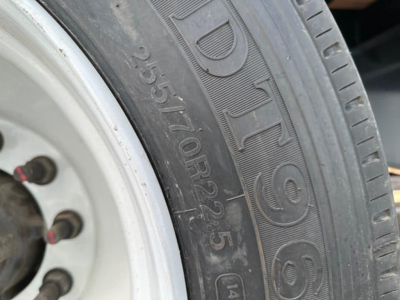 Tire sidewall showing DOT-style numbers and partial wheel hub on a trailer, with beavertail drop deck context.