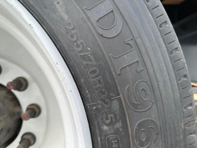 Truck trailer tire with visible sidewall markings and wheel, showing tire model and numerical codes.