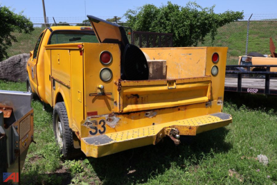 Rear view of a yellow Ford F-350 Super Duty utility truck with a open rear bed and toolbox compartments.
