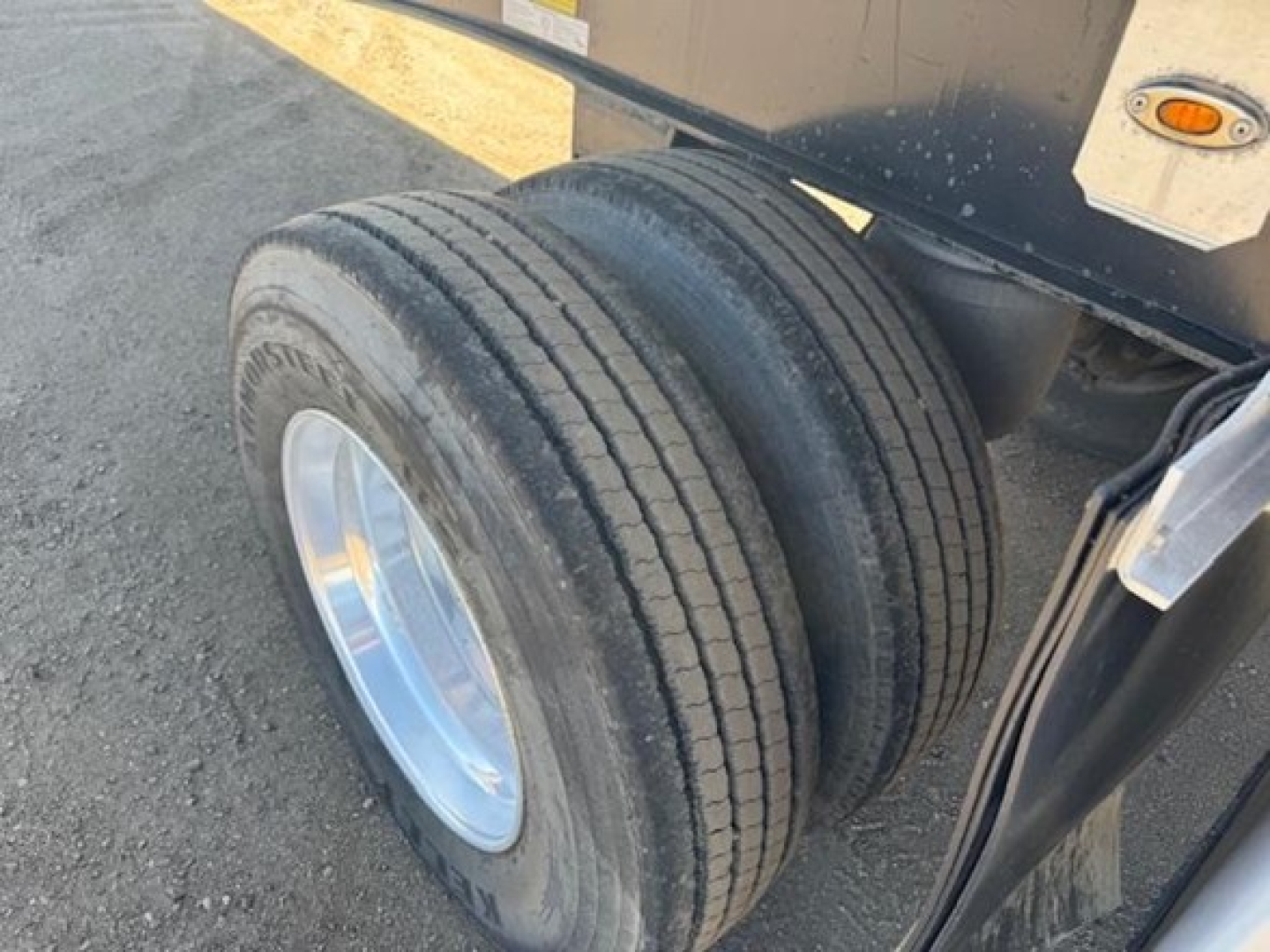 Dual rear axles with dual tires and a portion of a utility flatbed trailer frame visible.