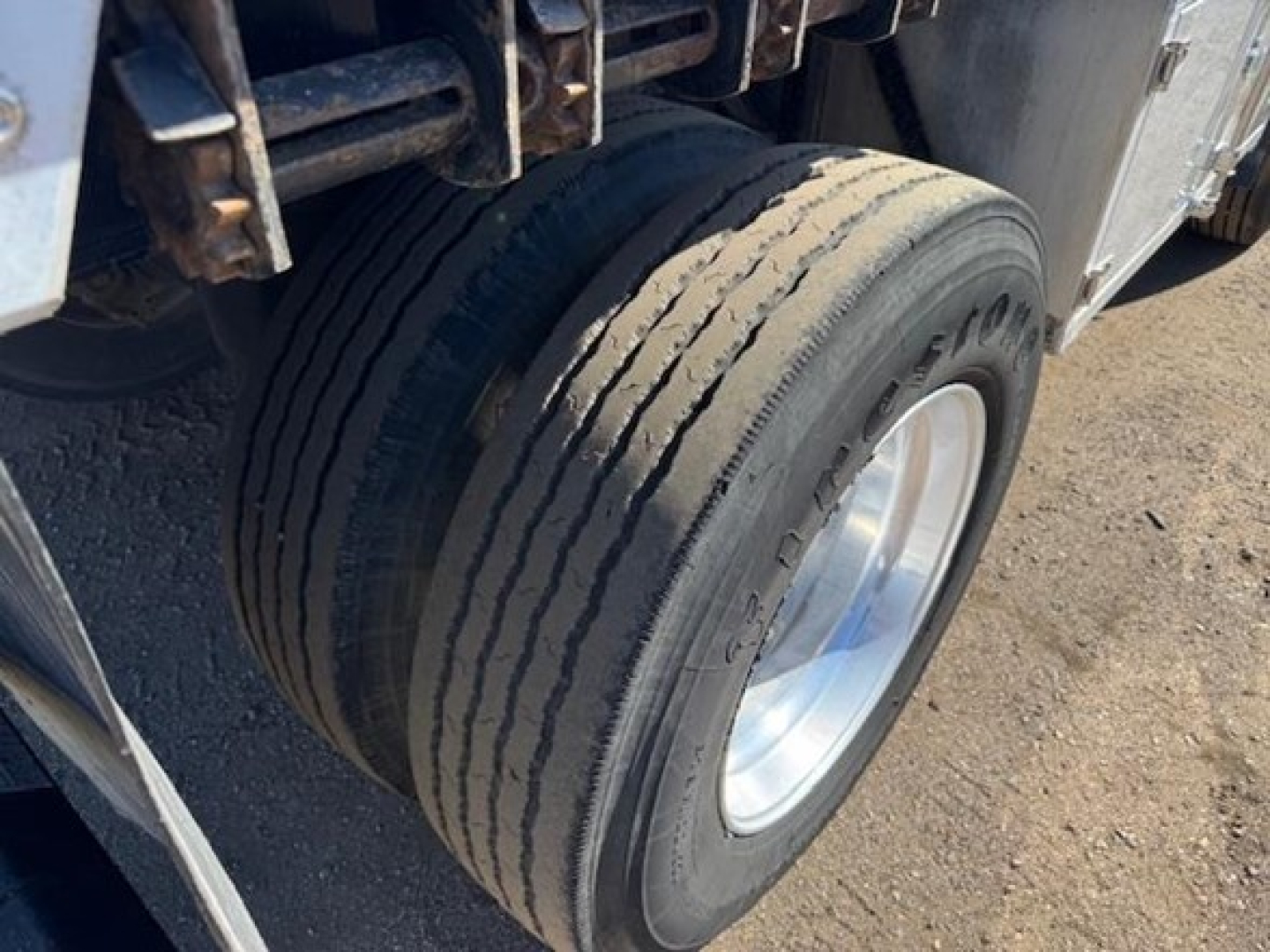 Utility 4000Ae trailer wheel and tire view showing dual-axle setup and metal framework.