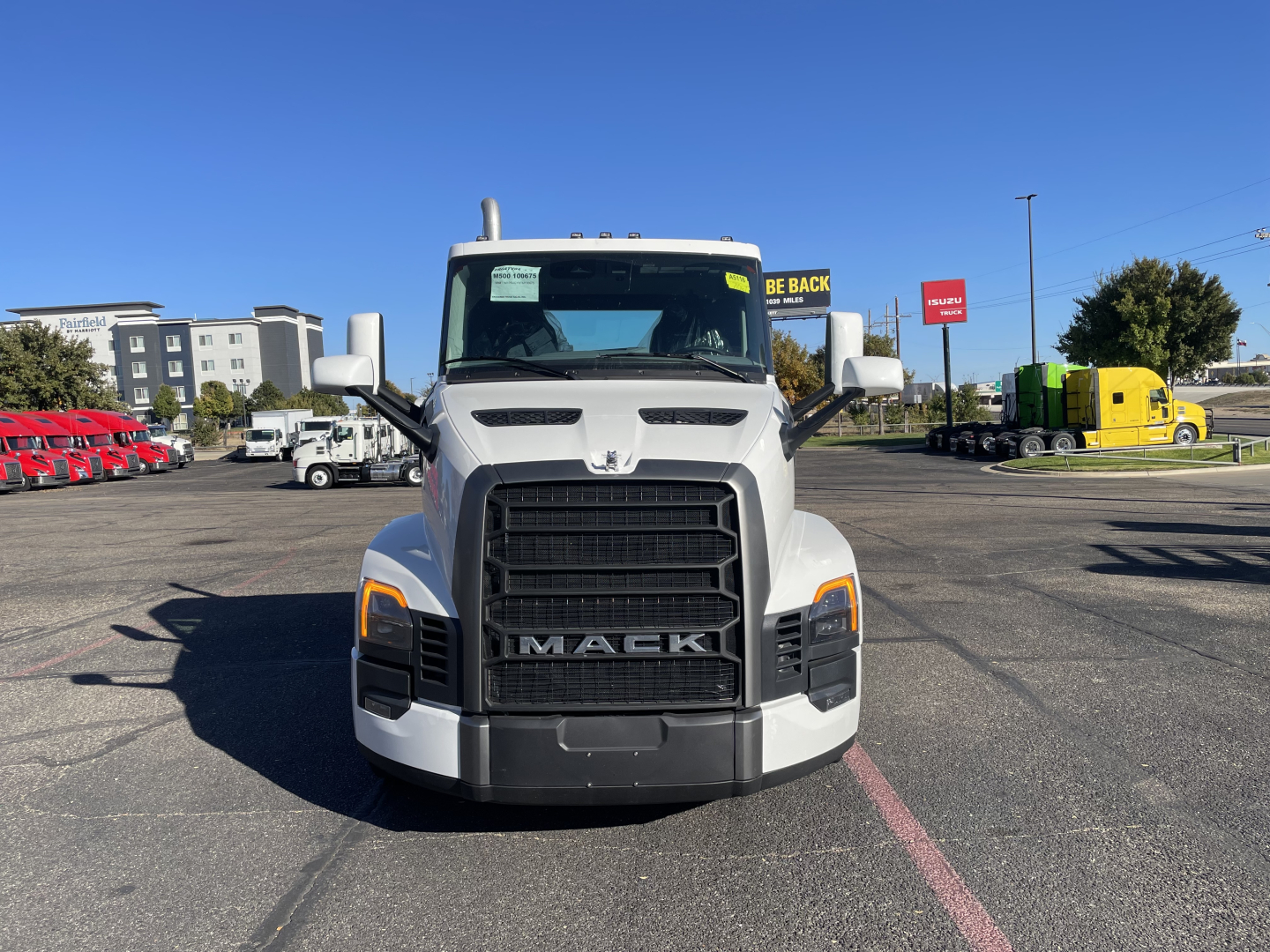 Front view of a white 2026 Mack PR64T truck with large black grille and headlights, in a dealership lot.