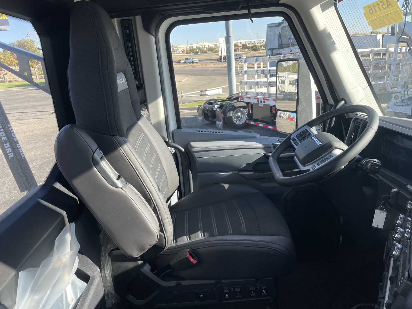 Cab interior of a 2026 Mack PR64T truck showing driver seat, steering wheel, dashboard, and control panel from the driver’s side.