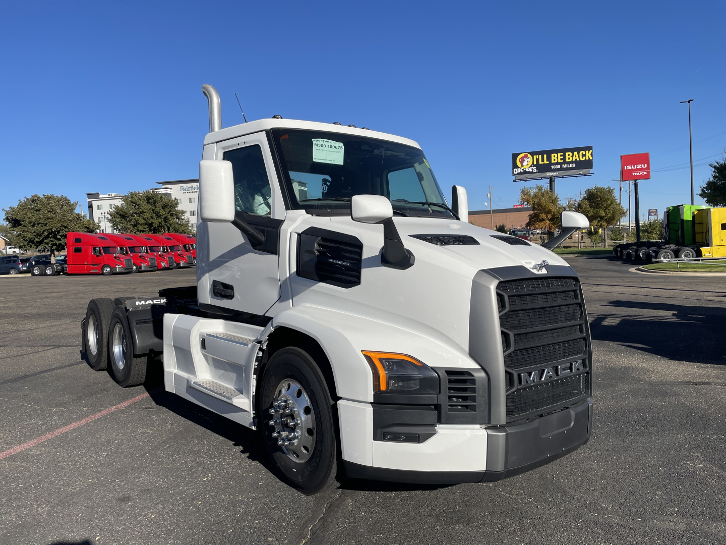 Mack PR64T truck front three-quarter view showing white cab, black grille, dual rear axles, and chrome fuel tanks.