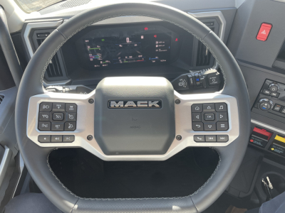 Mack PR64T truck cabin interior showing steering wheel with Mack logo and dashboard display.