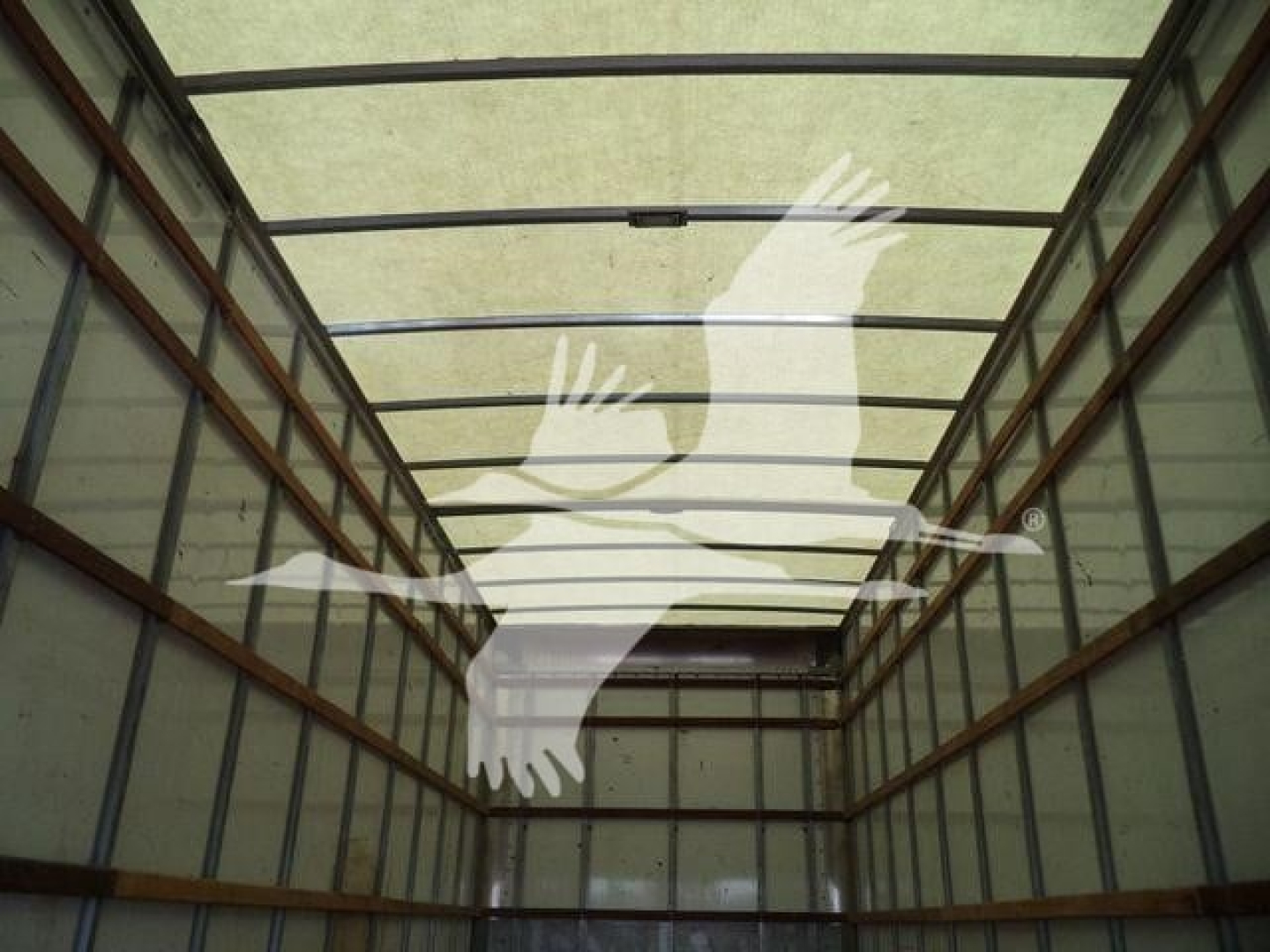 Cargo box truck interior trailer showing empty walls and ceiling framing in a dimly lit space.